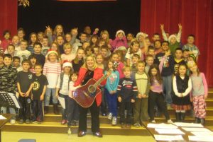 A group of children and an adult with a guitar.