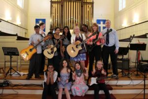 Four people singing outdoors in winter with songbooks.