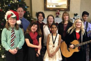 Four people singing outdoors in winter with songbooks.