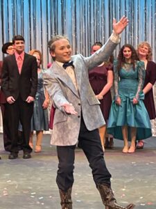 Four people singing outdoors in winter with songbooks.