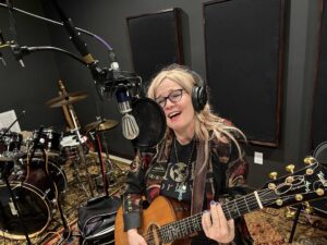 Four people singing outdoors in winter with songbooks.