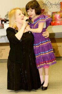 Four people singing outdoors in winter with songbooks.