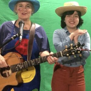 Four people singing outdoors in winter with songbooks.