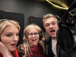 Four people singing outdoors in winter with songbooks.