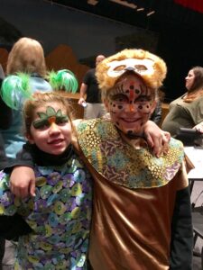 Four people singing outdoors in winter with songbooks.