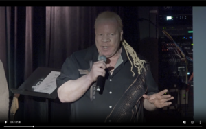 Four people singing outdoors in winter with songbooks.