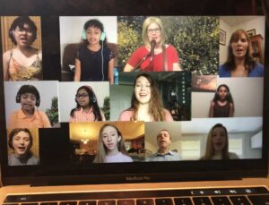 Four people singing outdoors in winter with songbooks.