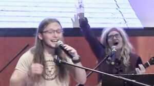 Four people singing outdoors in winter with songbooks.
