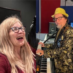 Four people singing outdoors in winter with songbooks.