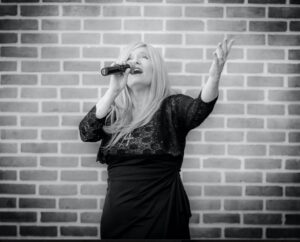 Black and white photo of a woman passionately singing with a microphone.